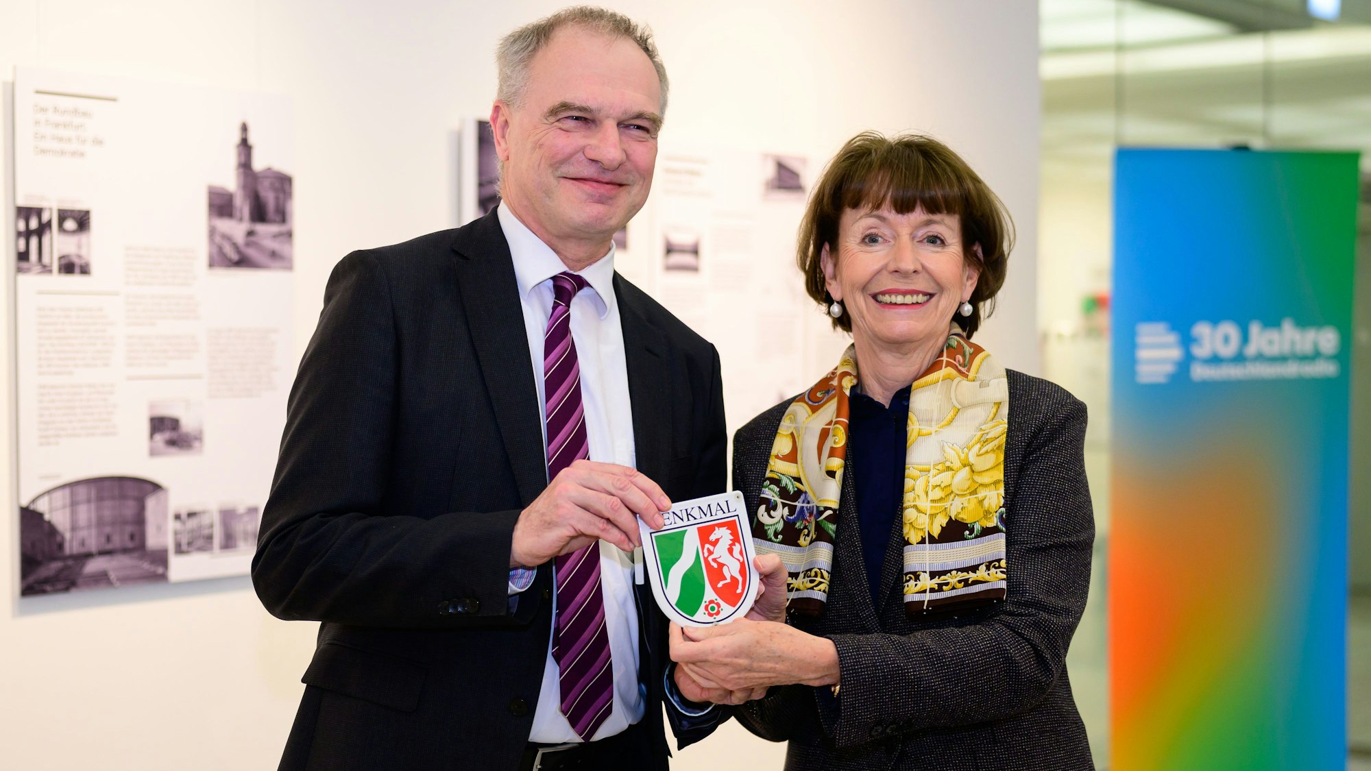 Ein Mann und eine Frau halten eine Plakette hoch.