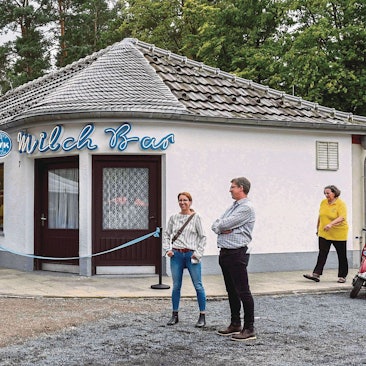 Zu sehen ist ein Gebäude, vor dem Menschen stehen.