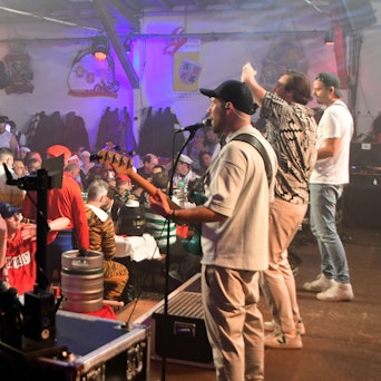 Die Band Lupo ist von schräg hinten zu sehen, vor ihnen das Publikum der Iversheimer Herrensitzung.