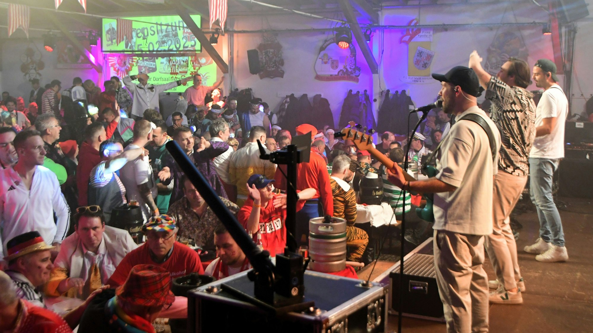 Die Band Lupo ist von schräg hinten zu sehen, vor ihnen das Publikum der Iversheimer Herrensitzung.