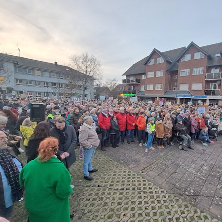 Karnevalisten, Pfadfinder, Mitglieder der Flüchtlingshilfe und viele andere Niederkasselerinnen und Niederkasseler stehen mit Transparenten vor dem Rathaus und demonstrieren.