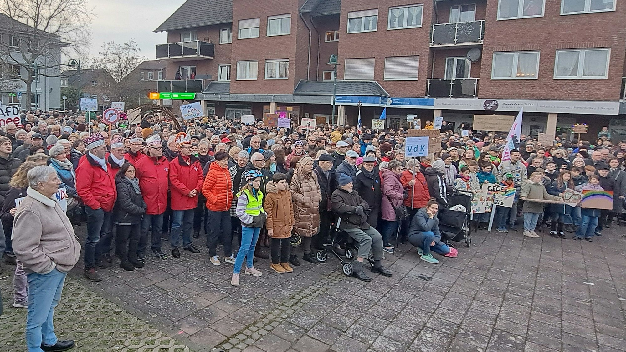 Karnevalisten, Pfadfinder, Mitglieder der Flüchtlingshilfe und viele andere Niederkasselerinnen und Niederkasseler stehen mit Transparenten vor dem Rathaus und demonstrieren.
