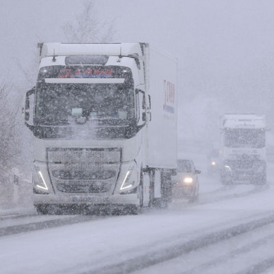 Mehrere Fahrzeuge sind bei starkem Schneefall auf einer Bundesstraße in der Eifel unterwegs. Die Fahrbahn ist zu großen Teilen mit Schnee bedeckt.