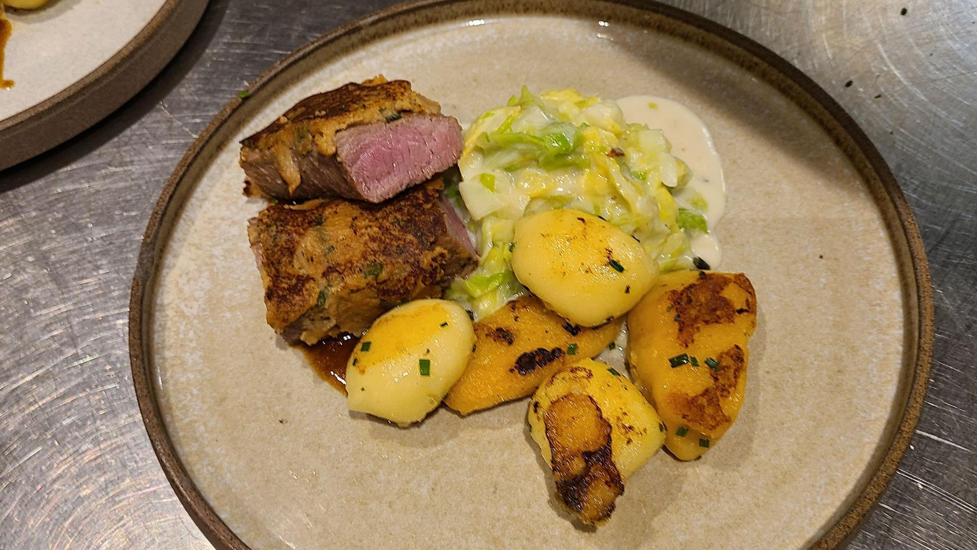 Auf dem Foto ist die Hauptspeise zu sehen: Lammrücken unter der Kräuterkruste mit Rahmspitzkohl und hausgemachten Gnocchi.