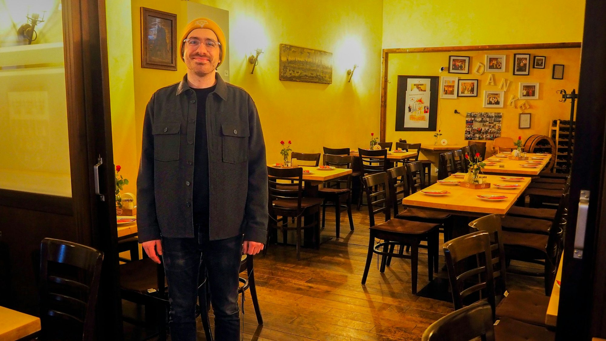 Ein Mann mit Mütze und Brille steht im Gastraum eines Brauhauses.