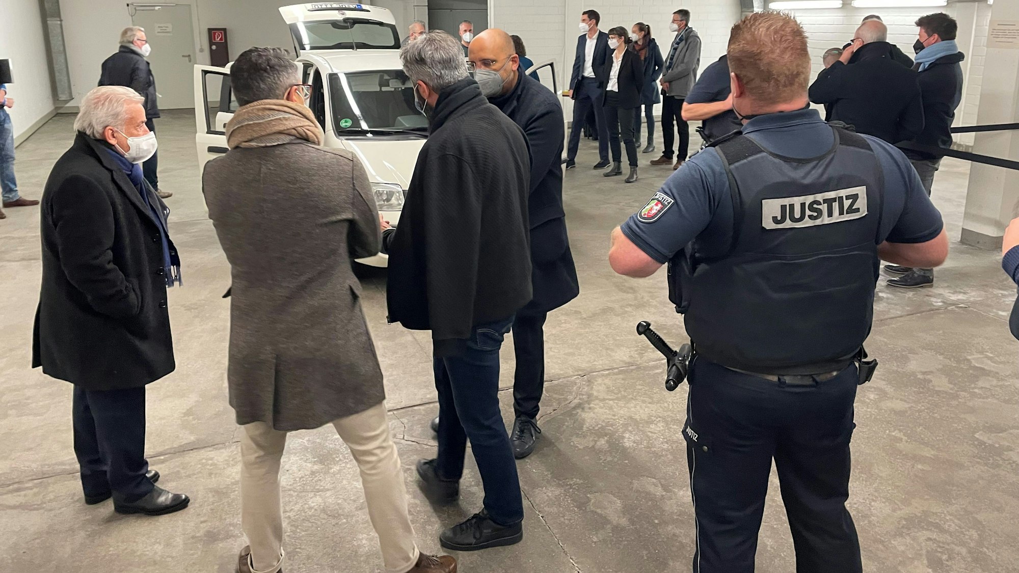 Leute stehen um ein geöffnetes Auto drumherum.