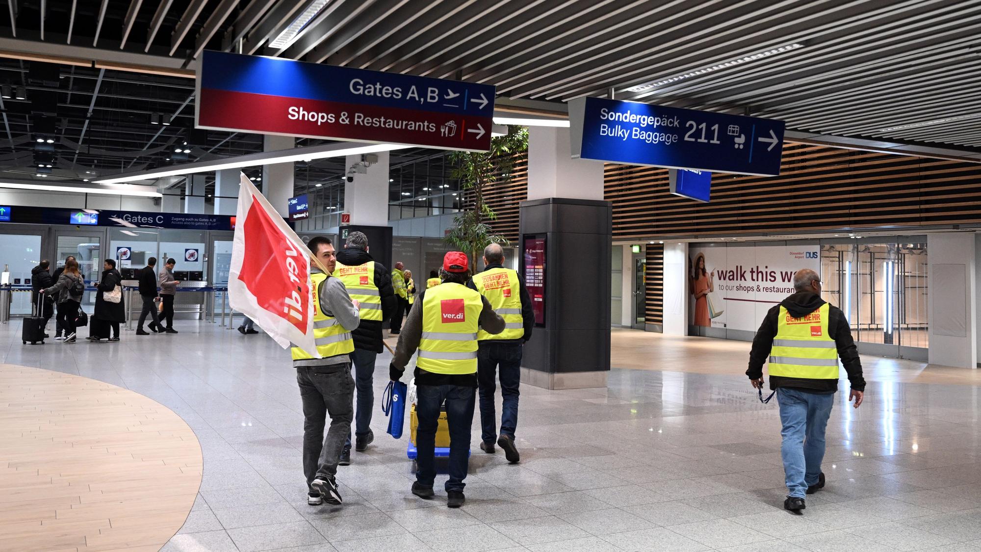 Streikende Flughafenmitarbeiter gehen durch das Terminal.