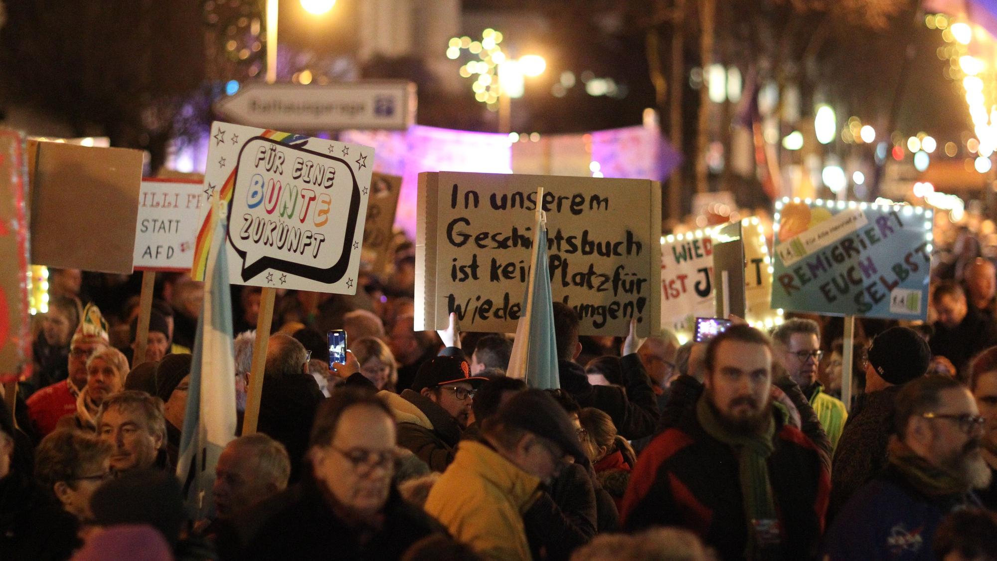 Menschen halten bei einer Demonstration Schilder in die Luft.