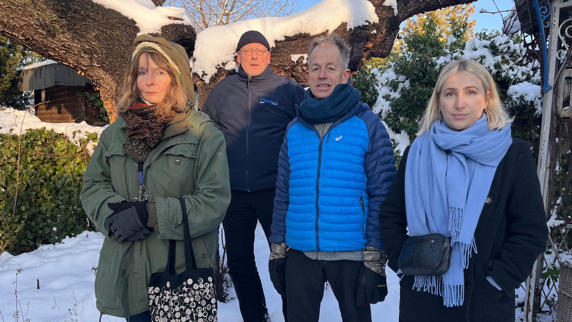 Zwei Frauen und zwei Männer stehen vor einem verschneiten Garten-Gelände.