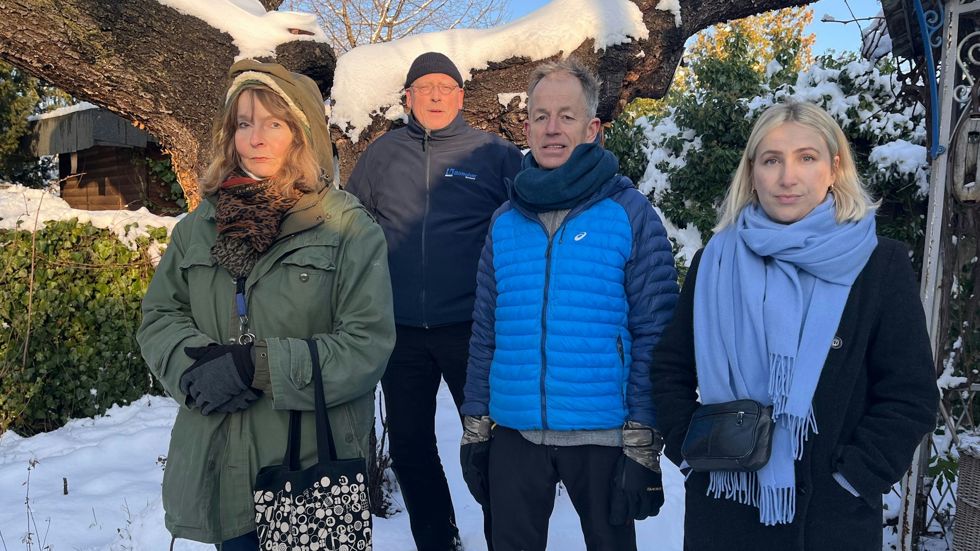 Zwei Frauen und zwei Männer stehen vor einem verschneiten Garten-Gelände.