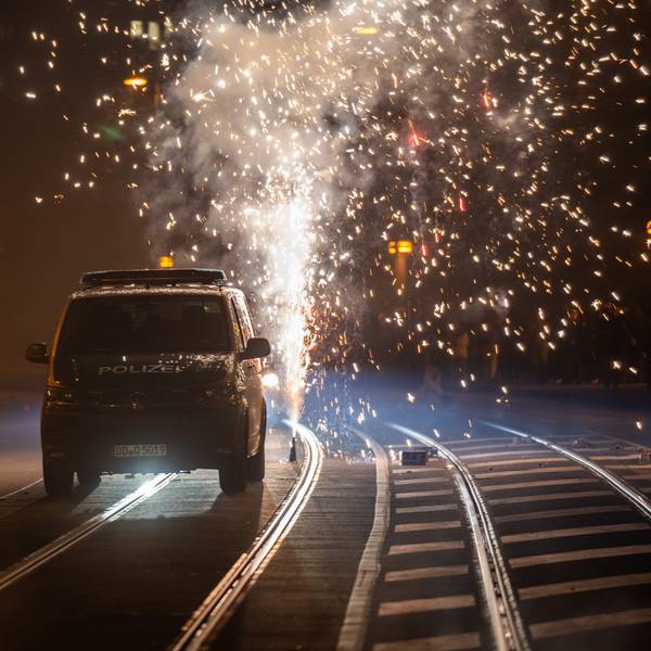 Hinter einem Polizeiauto wird Feuerwerk gezündet.