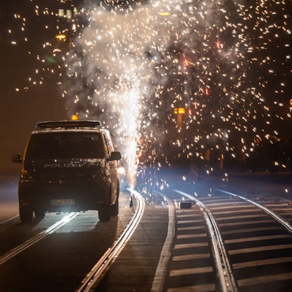 Hinter einem Polizeiauto wird Feuerwerk gezündet.