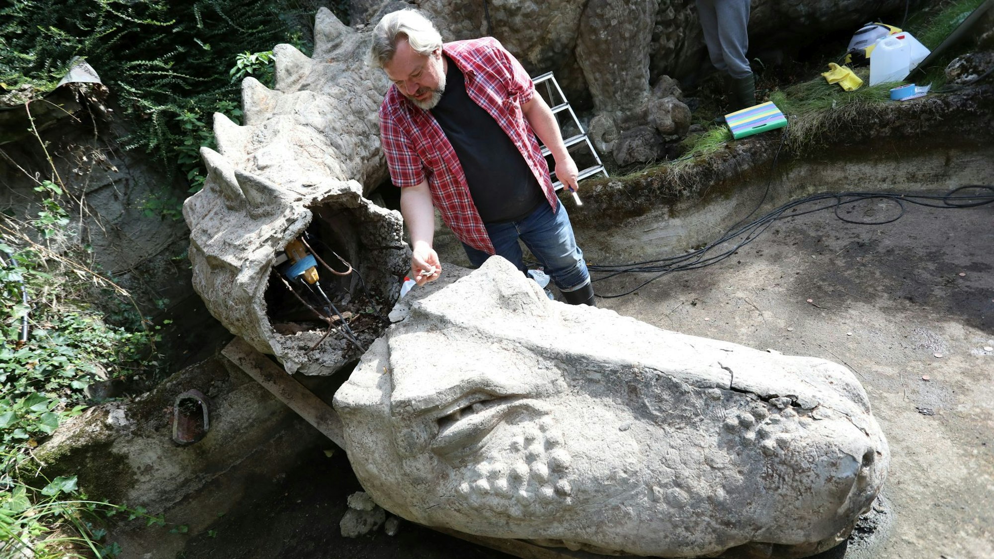 Der abgebrochene Kopf eines Drachen aus Beton und ein Restaurateur