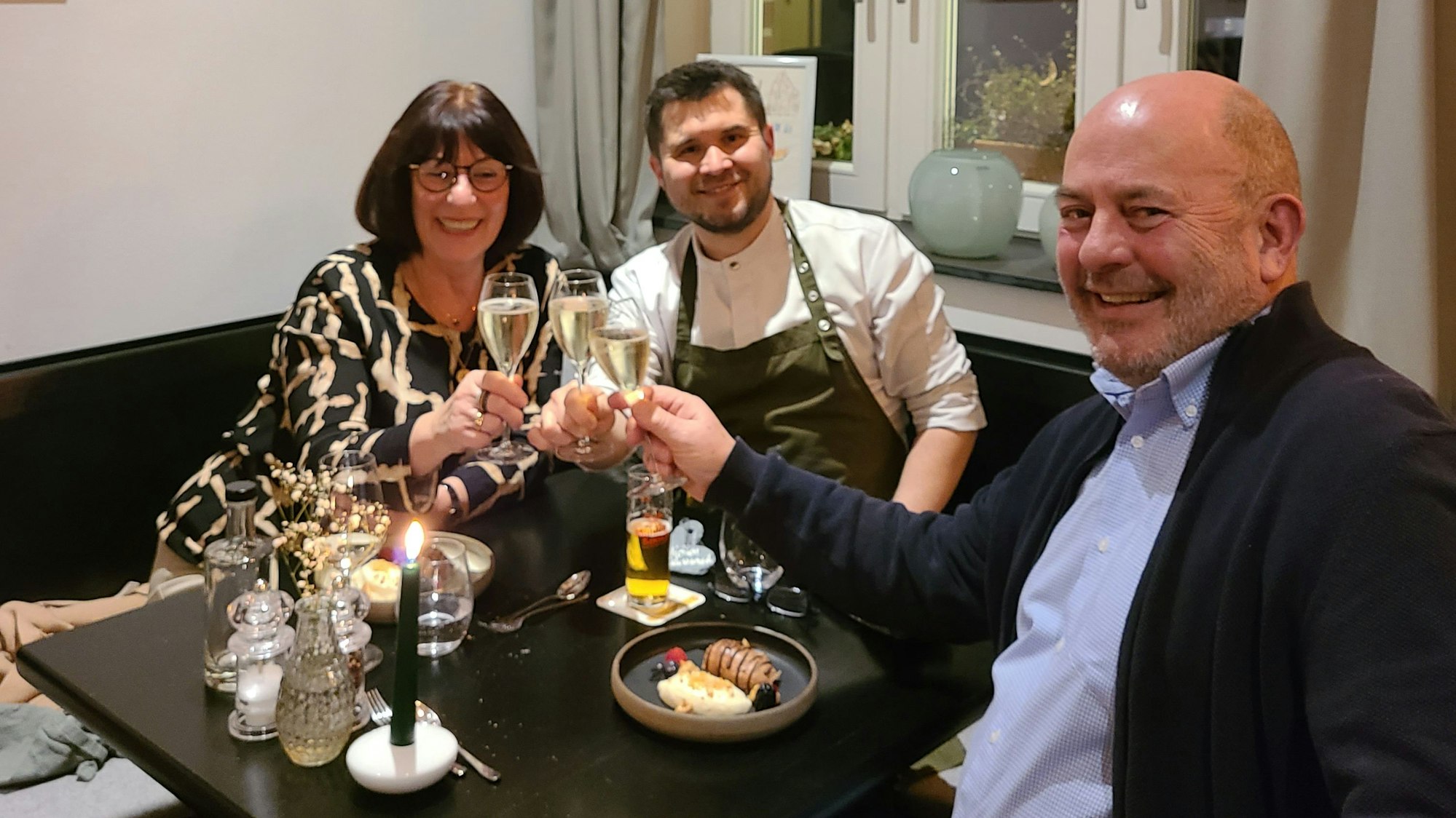 Auf dem Foto sind Sigrid und Wolfgang Wirtz aus Elsdorf zu sehen. Sie stoßen mit Gastronom Christof Hölscher (Mitte) auf einen gelungenen Abend an.