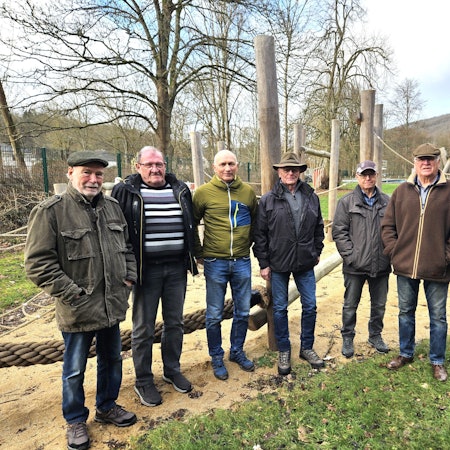 Sechs Männer, die „Rentner von Gemünd“, stehen auf einem Spielplatz.