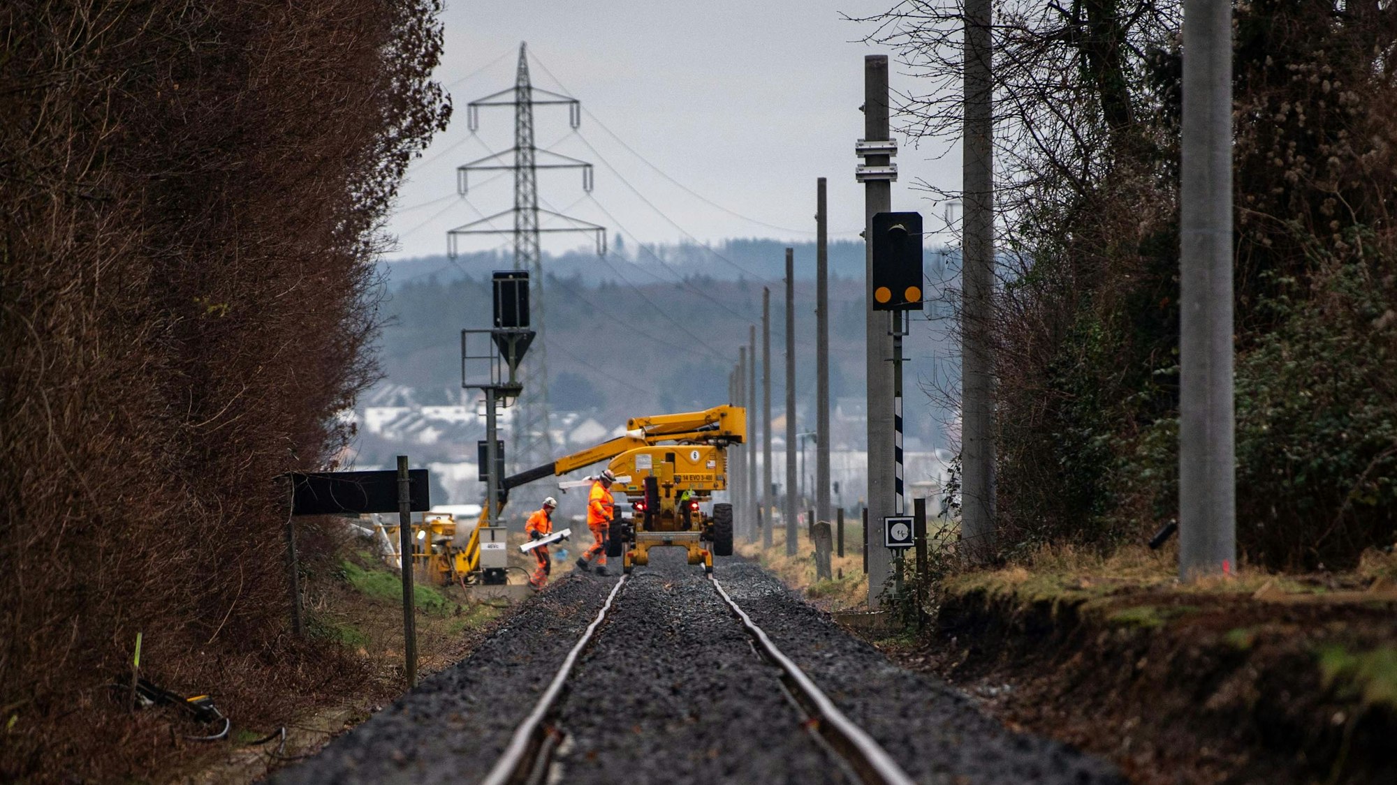 Arbeiter der Bahn bei der Sanierung der Bahnstrecke zwischen Euskirchen und Bad Münstereifel. Im Hintergrund ist der Mast einer Hochspannungsleitung zu sehen.