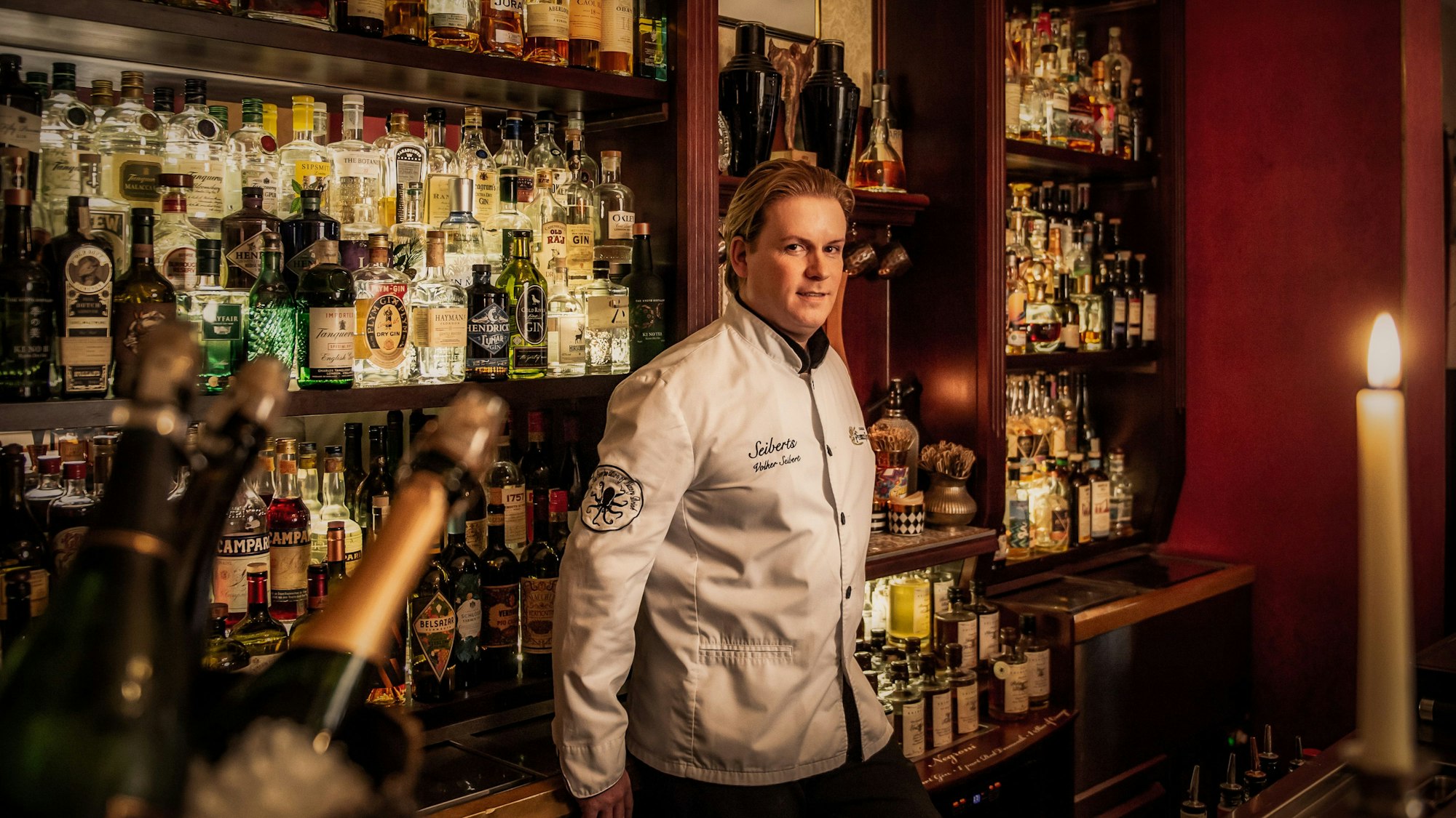 Volker Seibert vor den Getränkeflaschen hinter dem Tresen seiner Bar.