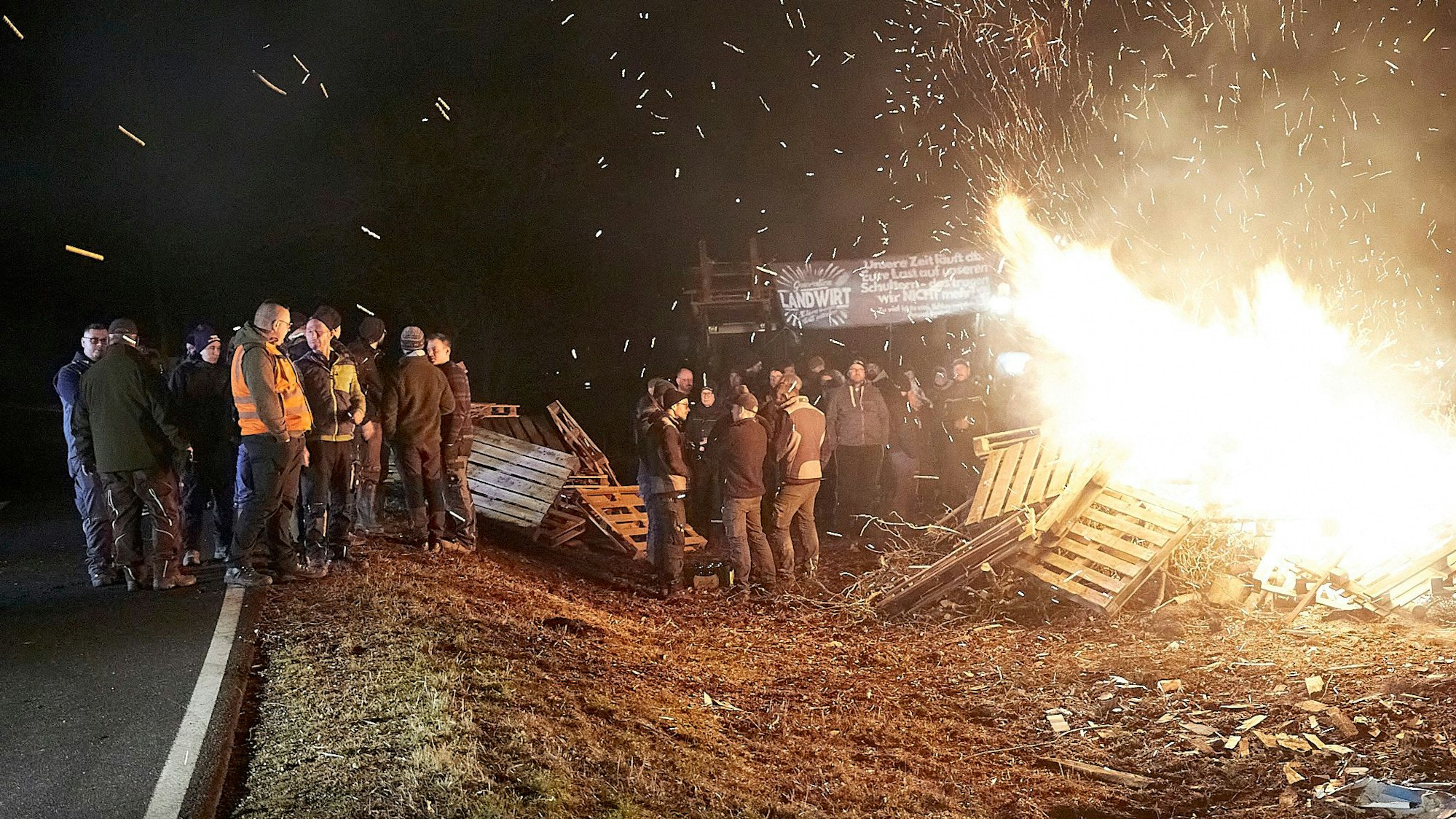 Eine Gruppe Menschen steht an einem Feuer: Mit diesen Mahnfeuern wie hier in Rescheid machen die Landwirte auf ihre Forderungen aufmerksam.