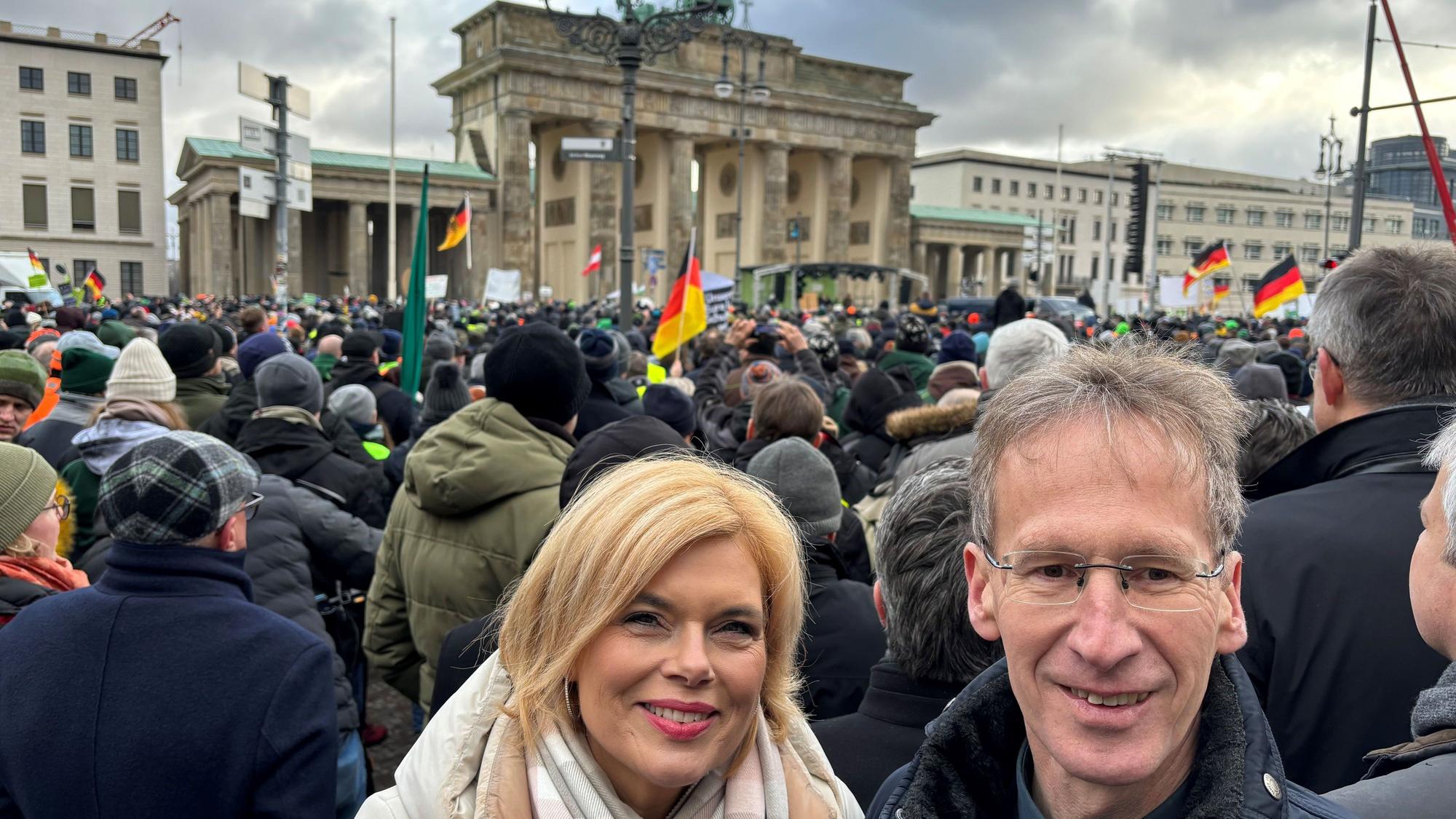 Das Bild zeigt Seif und Klöckner, dahinter demonstrieren Landwirte vor dem Brandenburger Tor.