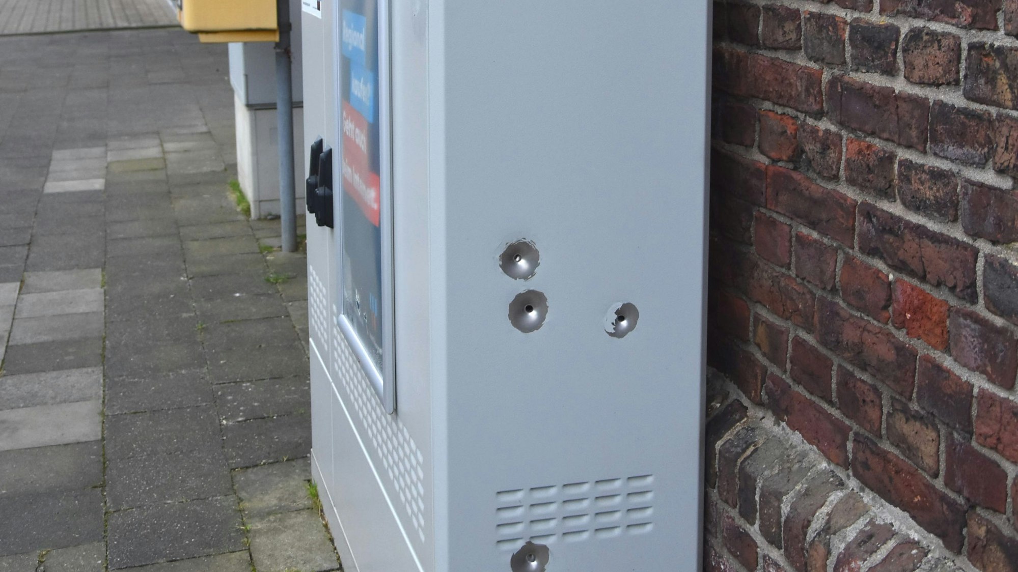 Auf dem Foto ist ein Glasfaser-Verteilerschrank zu sehen. An der Seite sind vier Einschusslöcher zu sehen.