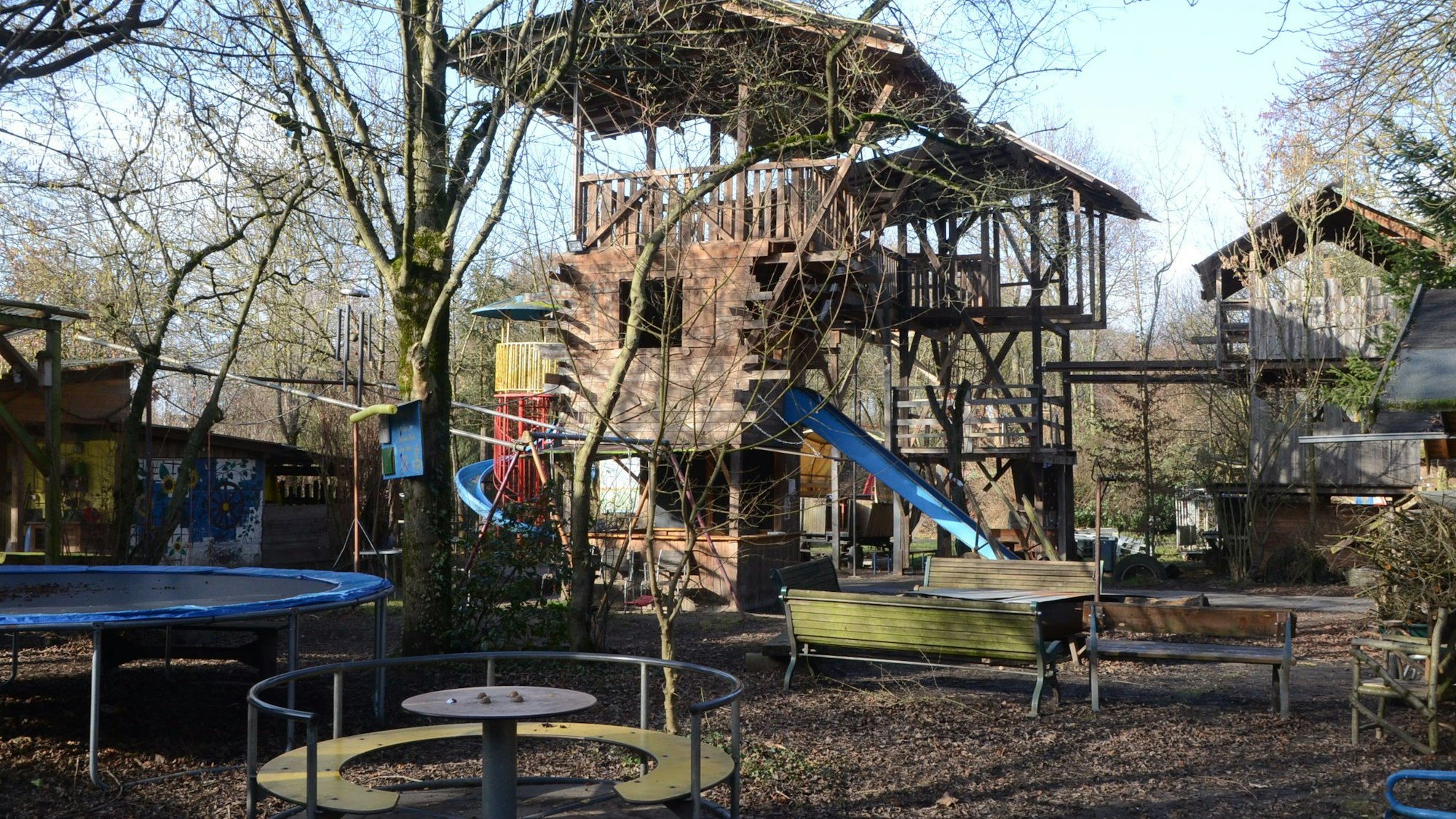 Kletterturm, Rutsche, Trampolin und Karussell auf einem Abenteuerspielplatz.
