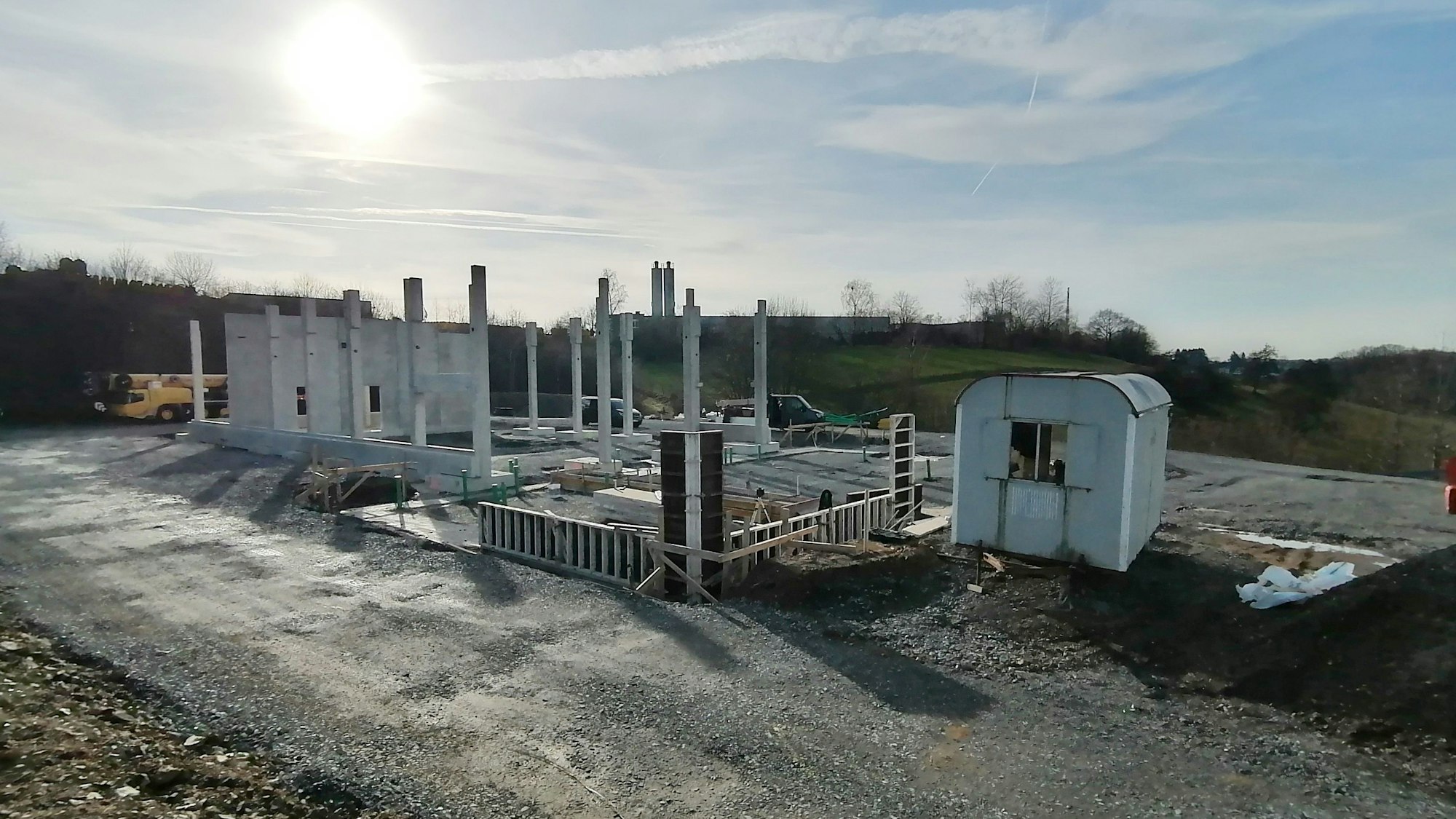 Ein im Bau befindliches Gebäude. Im Hintergrund steht die Sonnne am Himmel.