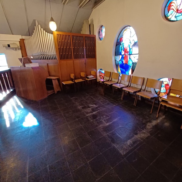 Zu sehen ist die Orgel-Empore in einer Kirche, an einer Wand stehen Stühle.