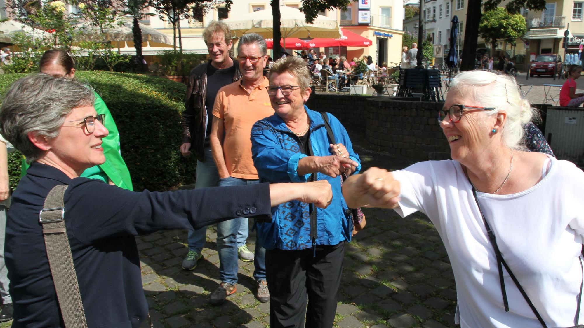Zwei Frauen strecken sich zur Begrüßung Faust und Ellbogen entgegen