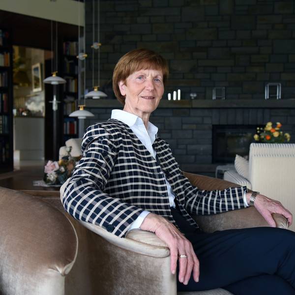 Eine Dame sitzt im Sessel eines Wohnzimmers.