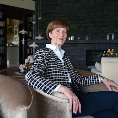 Eine Dame sitzt im Sessel eines Wohnzimmers.