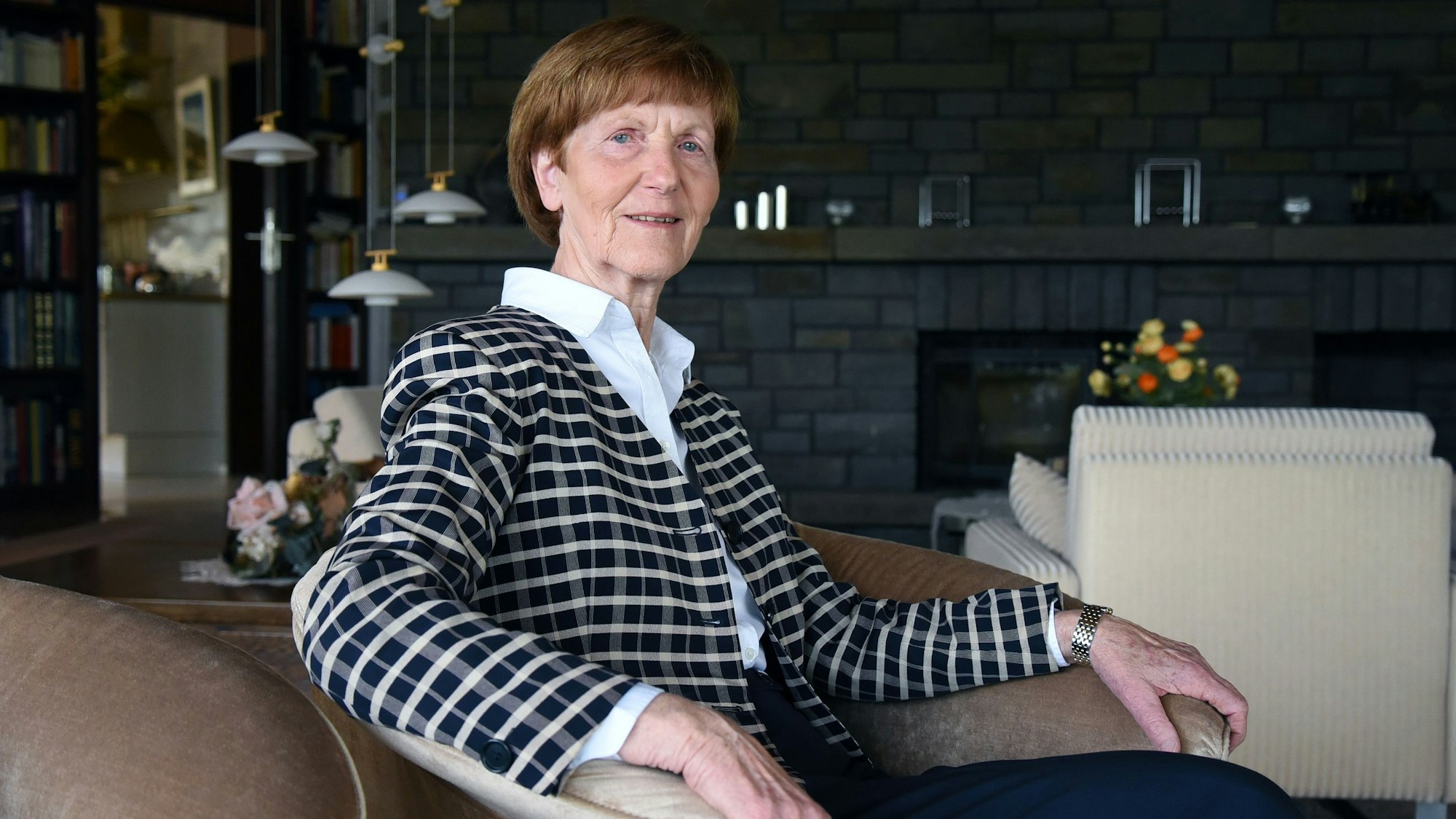 Eine Dame sitzt im Sessel eines Wohnzimmers.