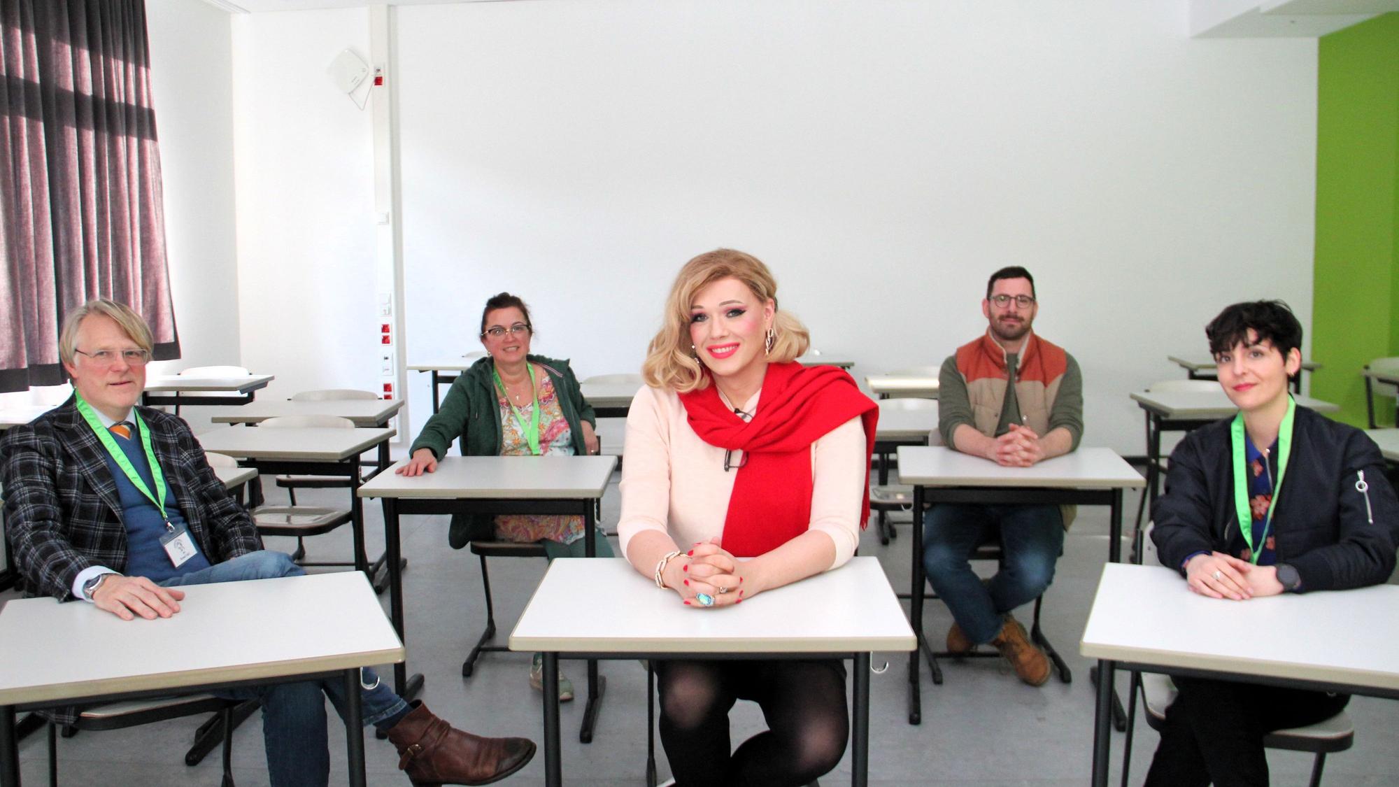 Mehrere Lehrerinnen und Lehrer sitzen an Tischen. In der Mitte sitzt die Künstlerin Cassy Carrington.