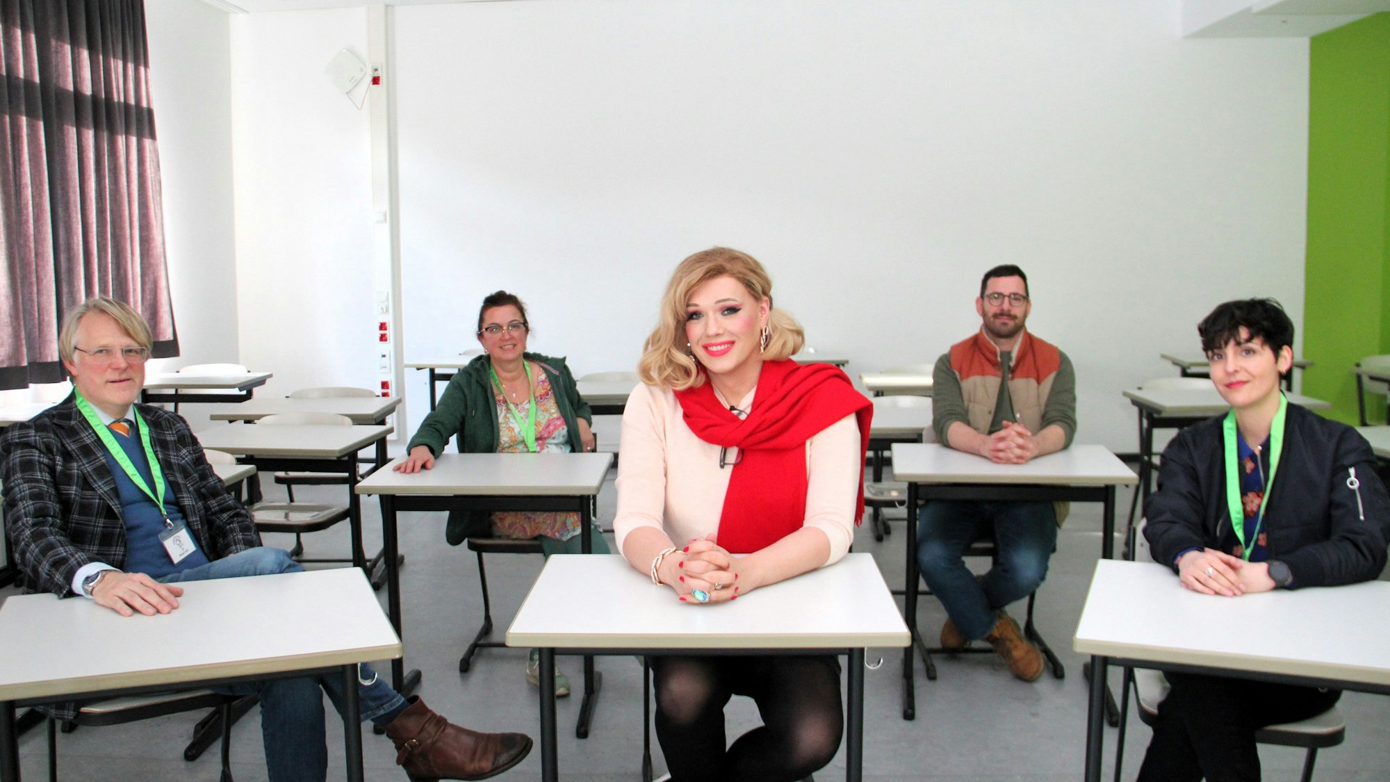 Mehrere Lehrerinnen und Lehrer sitzen an Tischen. In der Mitte sitzt die Künstlerin Cassy Carrington.