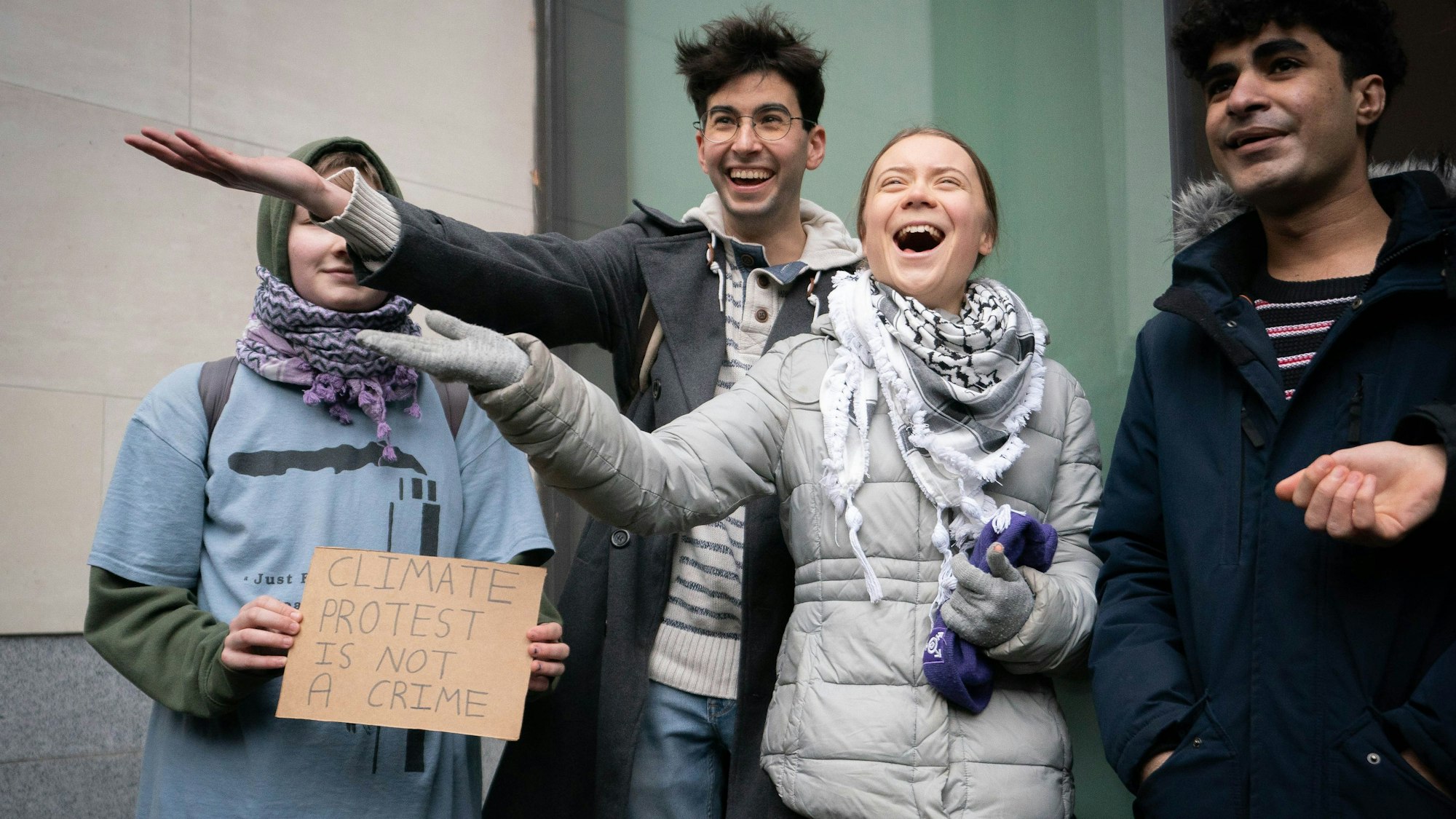 Greta Thunberg (M), Klimaaktivistin aus Schweden, lacht und streckt eine Hand aus, als sie vor dem Westminster Magistrates Court eintrifft.