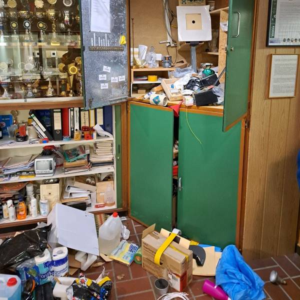Schränke sind nach einem Einbruch in Bedburg durchwühlt. Daneben ist eine Vitrine mit Pokalen zu sehen.