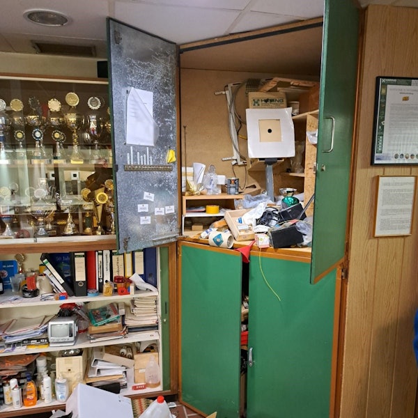 Schränke sind nach einem Einbruch in Bedburg durchwühlt. Daneben ist eine Vitrine mit Pokalen zu sehen.