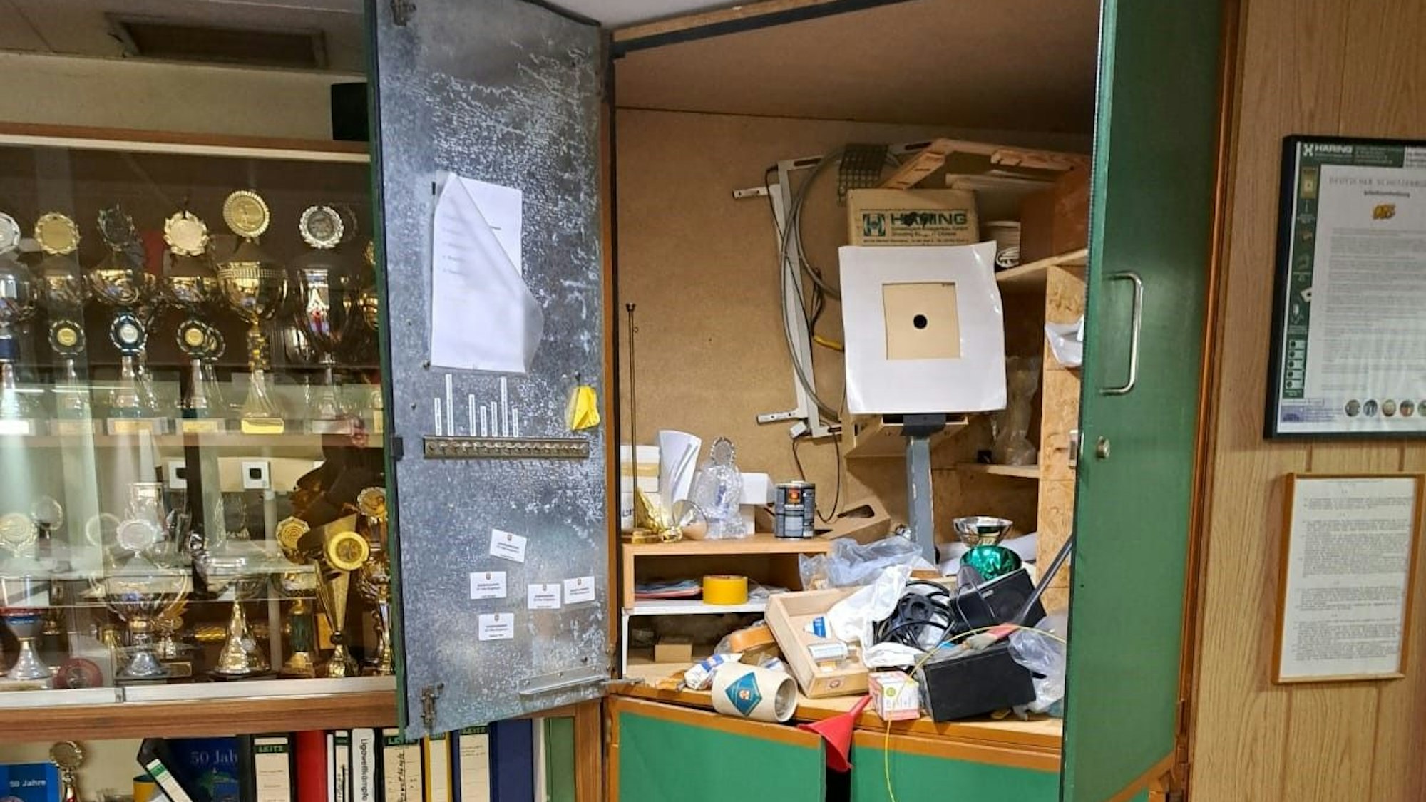 Schränke sind nach einem Einbruch in Bedburg durchwühlt. Daneben ist eine Vitrine mit Pokalen zu sehen.