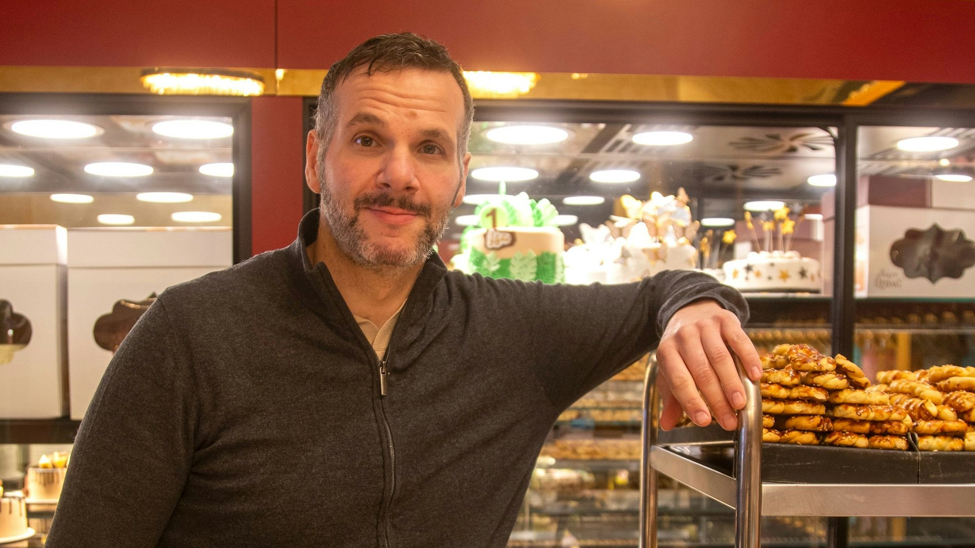 Ein Mann zwischen Gebäck und Kuchen.