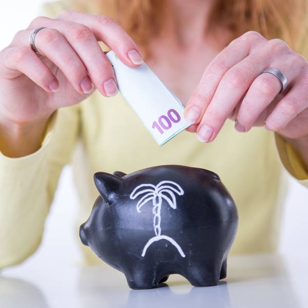 Eine Frau steckt einen 100-Euro-Schein in ein Sparschwein.