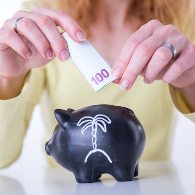 Eine Frau steckt einen 100-Euro-Schein in ein Sparschwein.