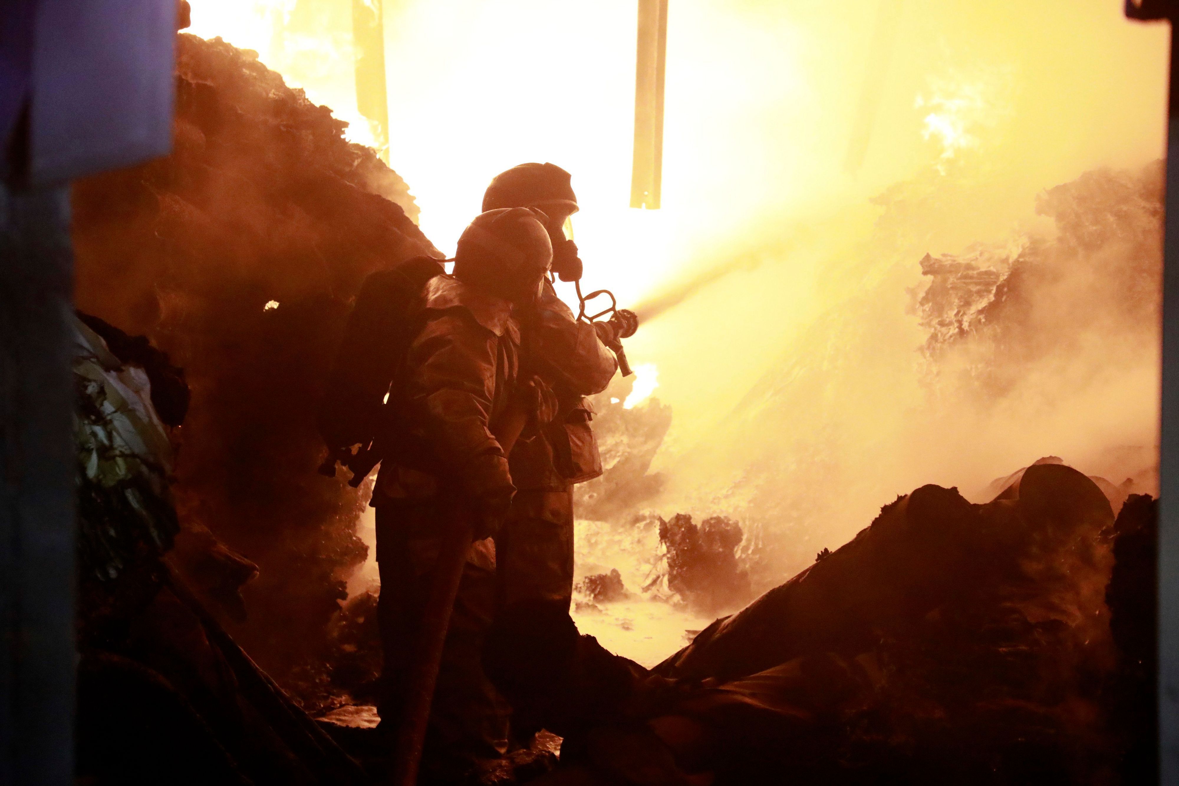 Feuerwehrleute löschen ein Feuer, das durch eine Explosion in einem Industriegebäude verursacht wurde.