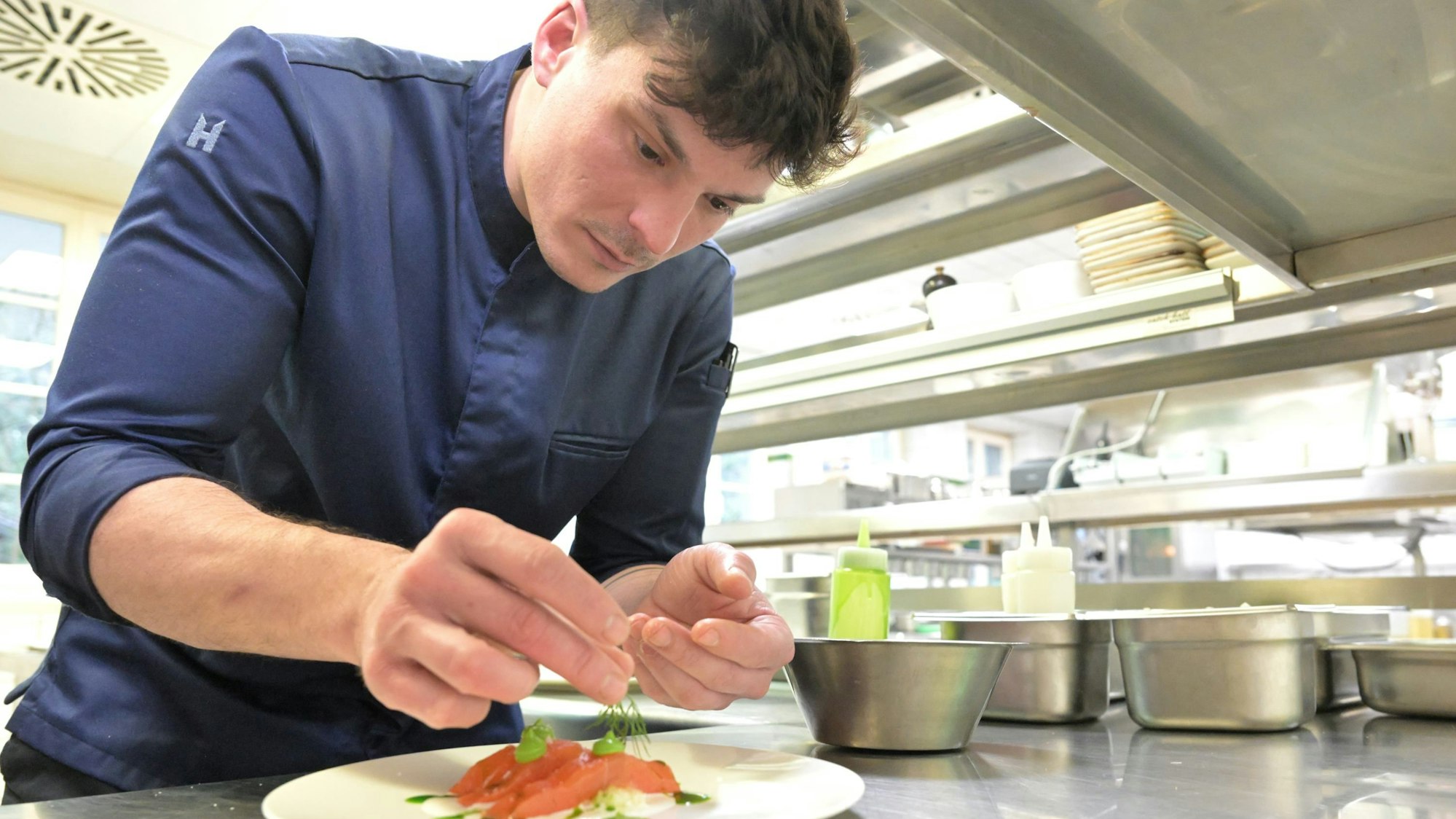 Der Küchenchef Christian Meinke richtet ein Stück Wipperfürther Lachsforelle auf dem Teller an.