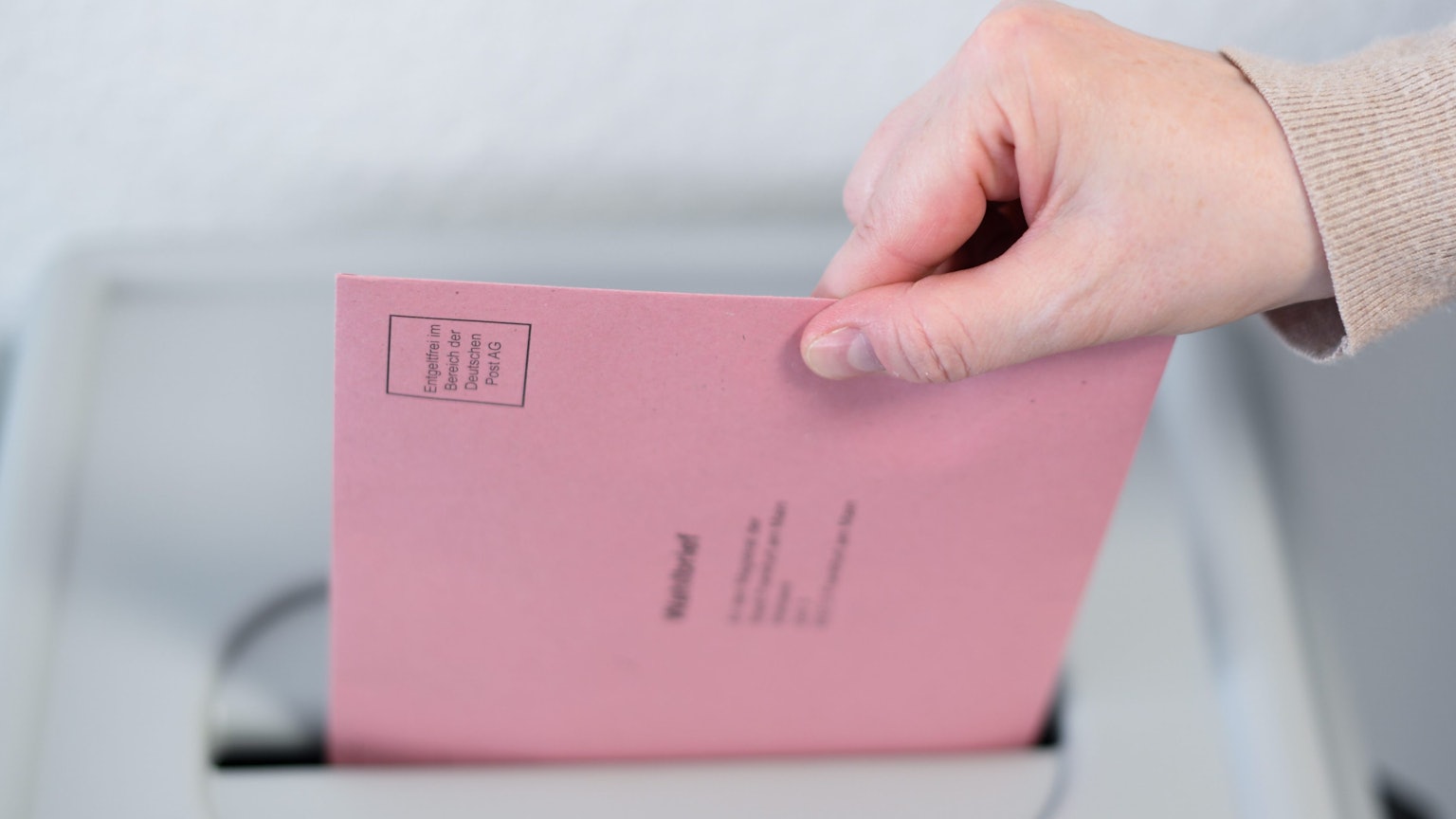 Eine Frau wirft ihren Wahlbrief in eine Wahlurne.