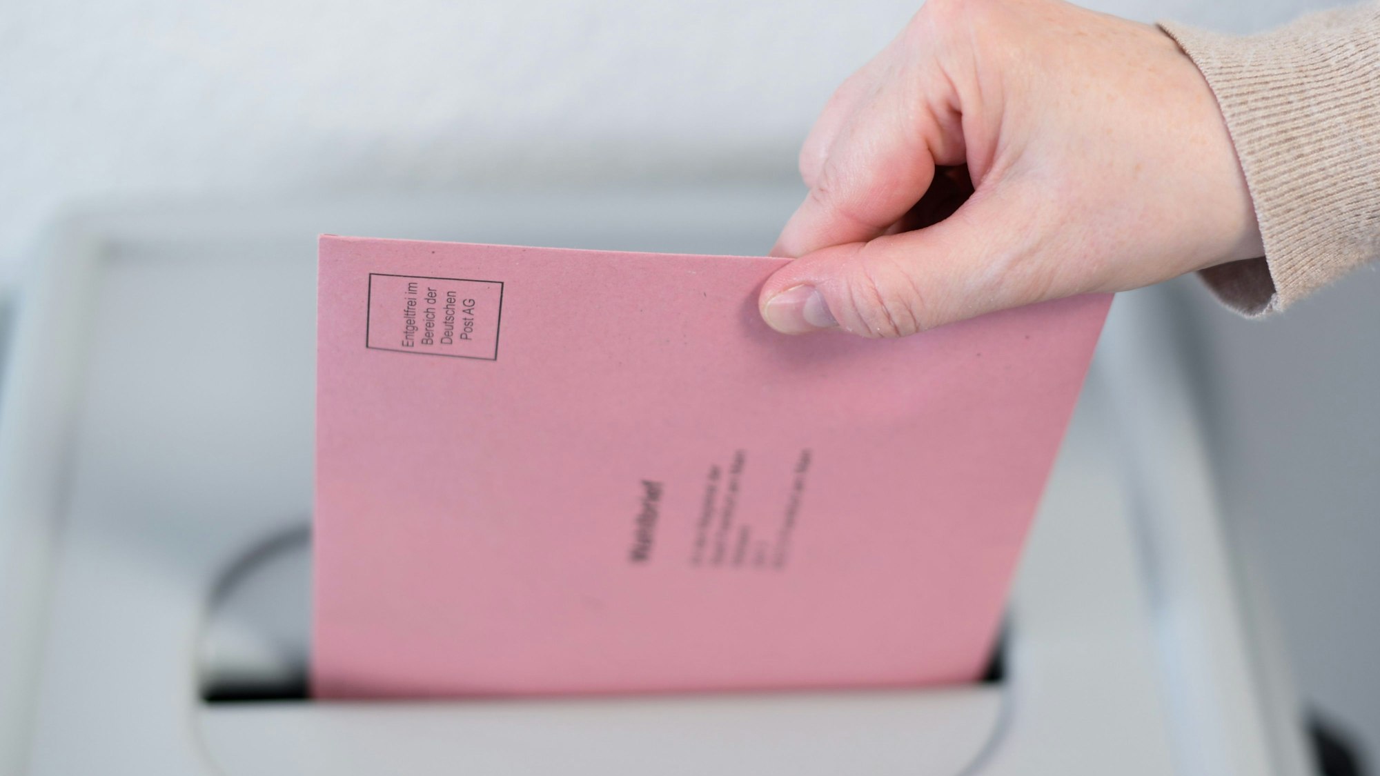 Eine Frau wirft ihren Wahlbrief in eine Wahlurne.