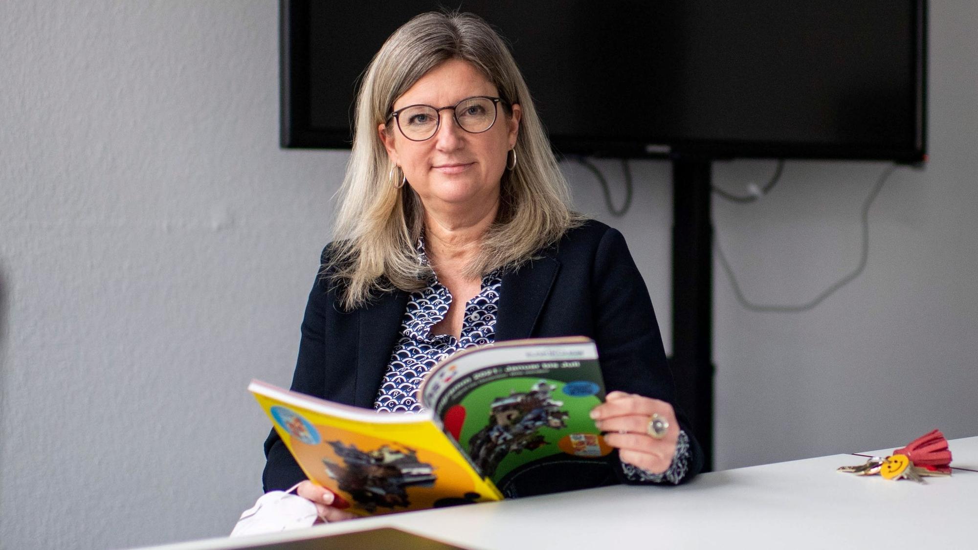 Vanessa Becker blättert in einem VHS-Programmheft.