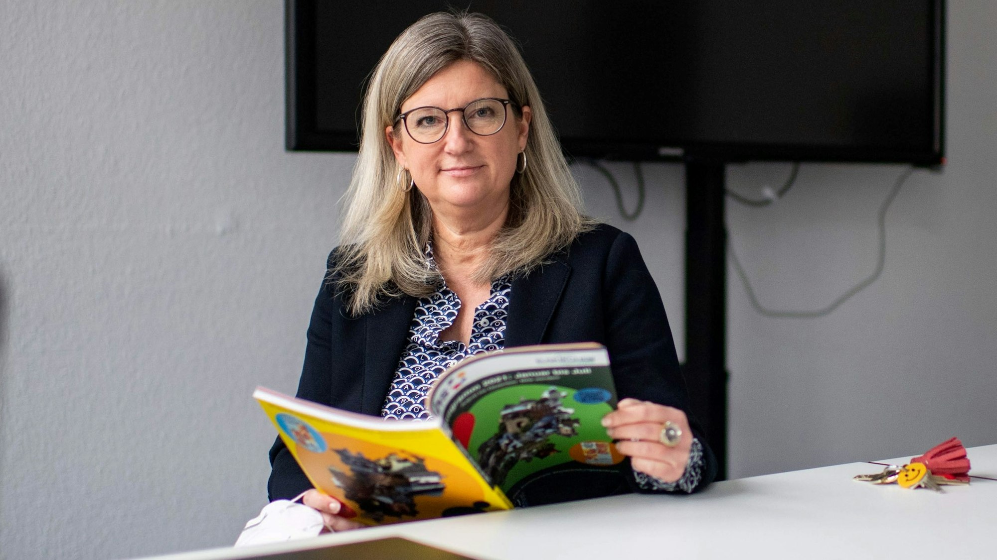 Vanessa Becker blättert in einem VHS-Programmheft.