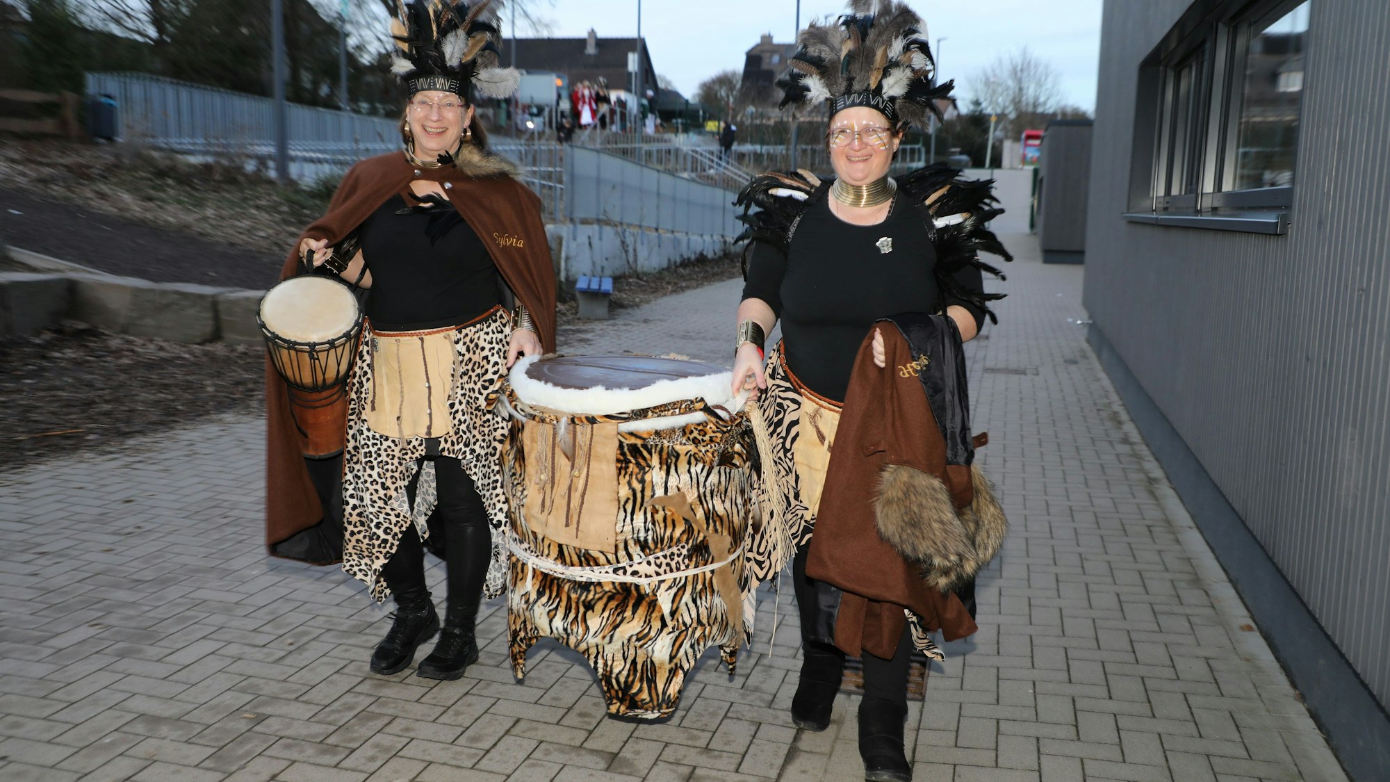 Zwei Frauen tragen eine große Trommel.