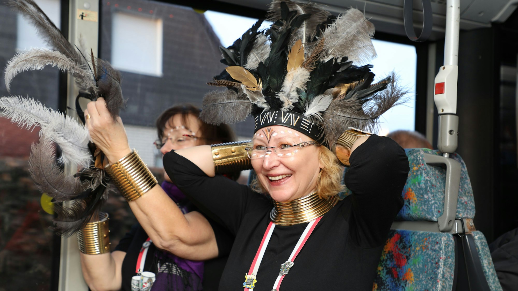 Eine Frau zieht in einem Linienbus ihr Kostüm an.