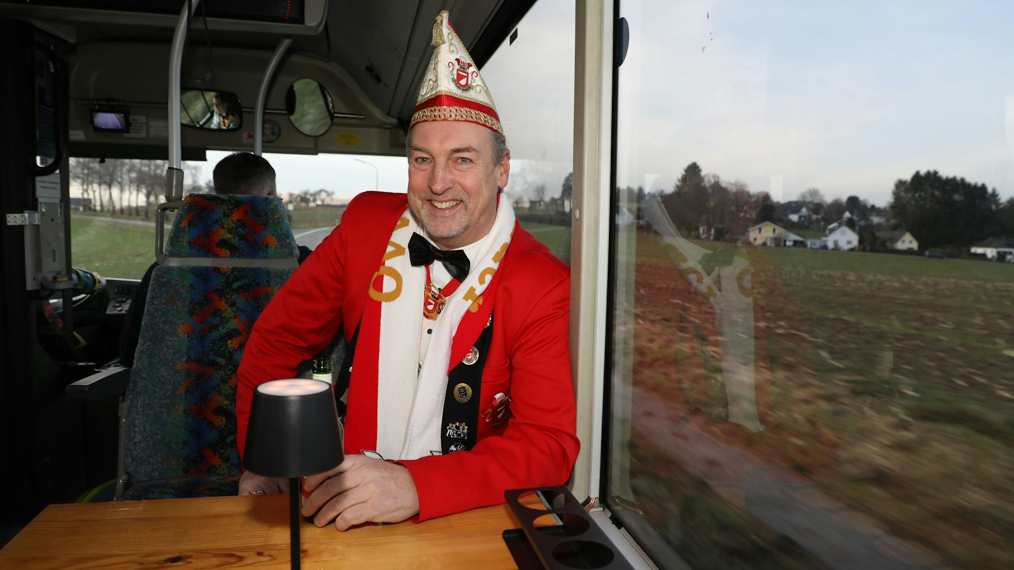 FKO-Präsident Peter Paas sitzt an einem Tisch im Partybus des Oberodenthaler Dreigestirns.