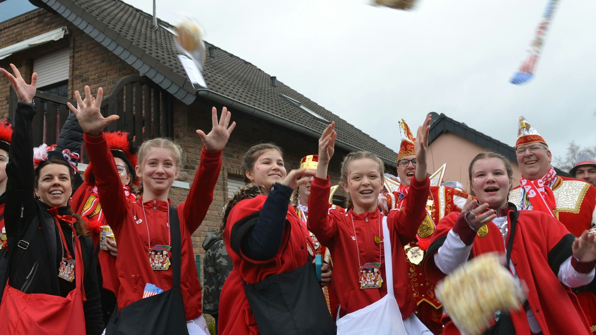 Mädchen in roten Kostümen verteilen Süßigkeiten.